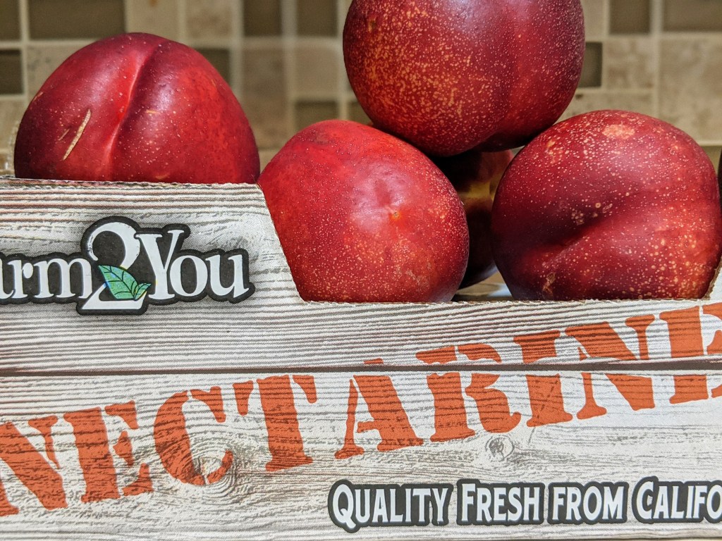 A juicy, plump pile of fresh nectarines in a crate. 