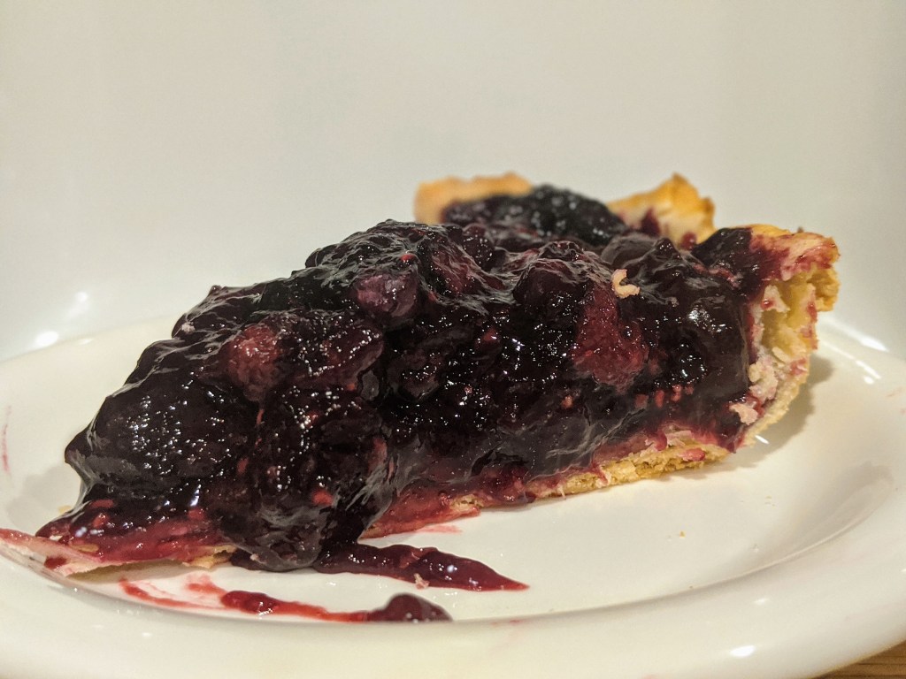 Slice of cherry berry pie, with a golden buttery crust ready to be devoured.