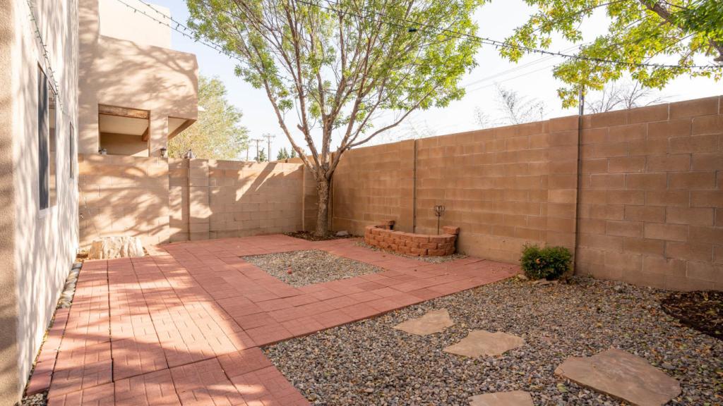 Exterior shot of the patio with brick pavers, string lights, and green trees.
